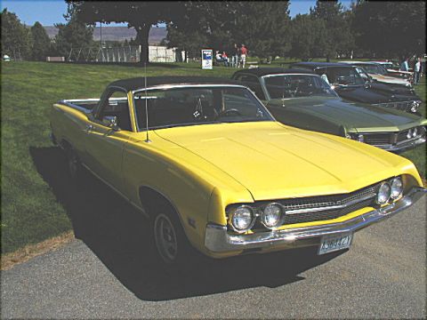 1967 Ford Ranchero - A yellow 1968 Ford Ranchero is parked on asphalt with a grassy area and trees in the background.