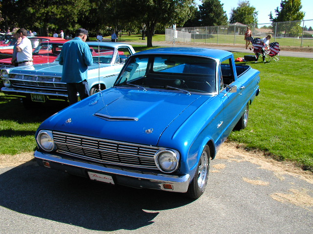 Blue 1966 Ford Ranchero pickup truck with chrome grille and hood scoops, parked on asphalt