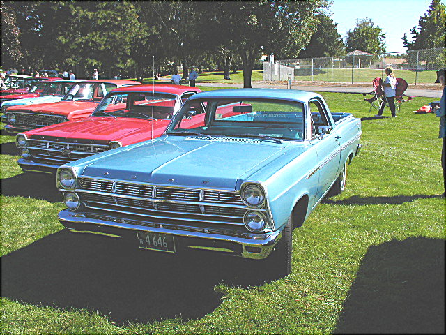 1967 Ford Ranchero in light blue parked on grass with other cars behind it