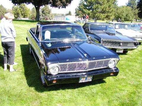 1967 Ford Ranchero - A black 1965 Ford Falcon Ranchero is displayed on a grassy field, with other vehicles in the background.