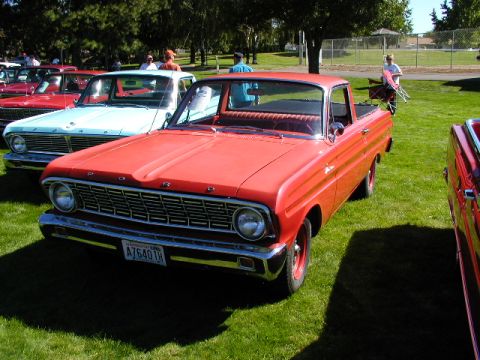 1967 Ford Ranchero - Red Ford Ranchero pickup at an outdoor car show, parked next to other vehicles.