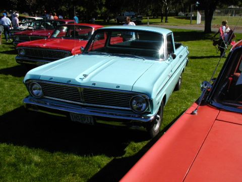1967 Ford Ranchero - A light blue 1964 Ford Falcon Ranchero pickup truck is parked on a grassy field, with other vehicles visible in the background.
