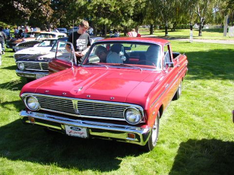 1967 Ford Ranchero - A red 1967 Ford Ranchero is parked on a grassy lawn with other vehicles nearby.