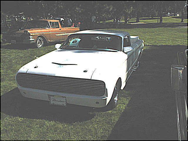 White early-1960s Ford Ranchero pickup on grass with orange two-tone Ford behind