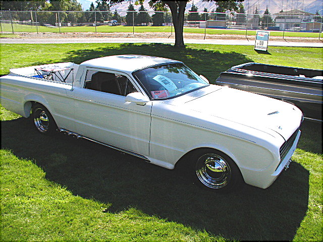 White 1967 Ford Ranchero pickup truck with chrome wheels and side pipes, parked on grass