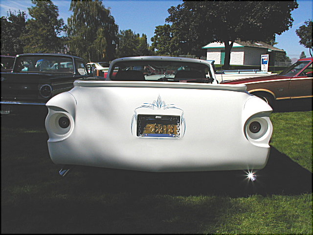 Rear of white custom coupe utility with frenched taillights and pinstriping at a car show