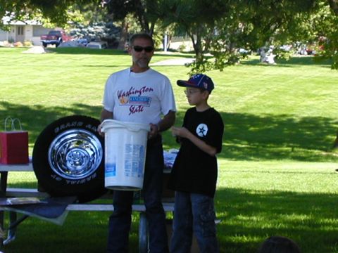 1967 Ford Ranchero - Man and boy at an outdoor event with a tire and bucket on a table.