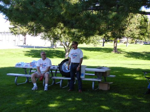 1967 Ford Ranchero - A spare tire with a chrome rim is displayed on a picnic table during an outdoor gathering.