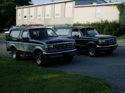 1992 Ford Bronco - Two Ford Broncos are parked next to each other in front of a building.