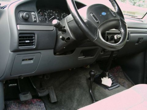1992 Ford Bronco - The interior of a 1992 Ford Bronco shows the dashboard, steering wheel, and manual transmission shifter.