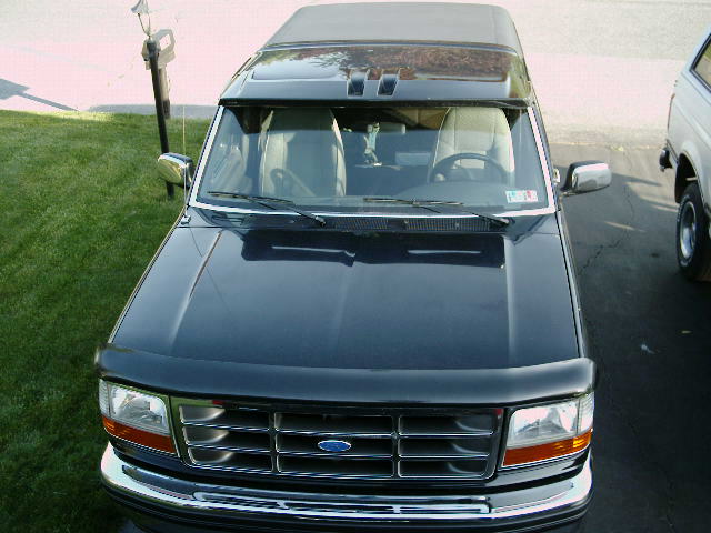 Overhead front view of a dark green Ford SUV hood, grille and windshield