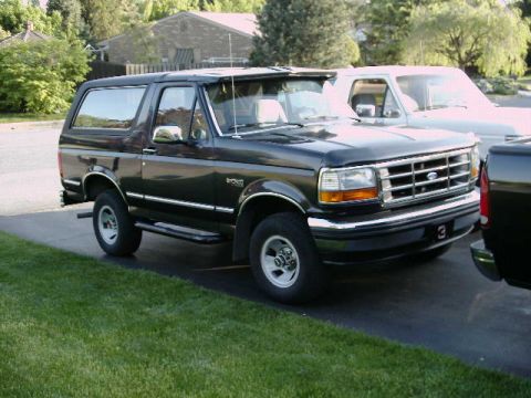 1992 Ford Bronco - A black 1992 Ford Bronco is parked in a driveway with a white truck behind it.