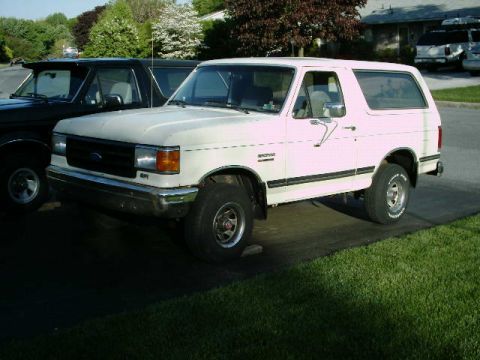 1988 Ford Bronco - White 1988 Ford Bronco parked on a driveway with a black truck beside it.