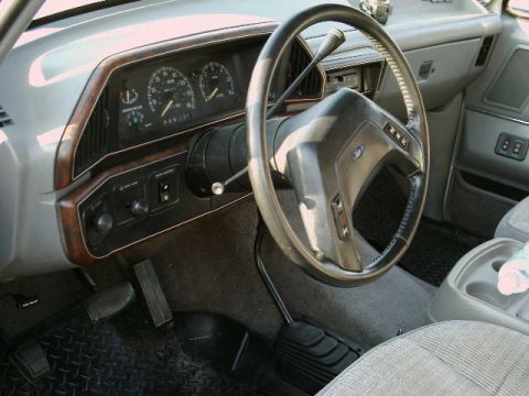 1988 Ford Bronco - The dashboard and interior of a 1988 Ford Bronco, wood grain trim and gray upholstery.