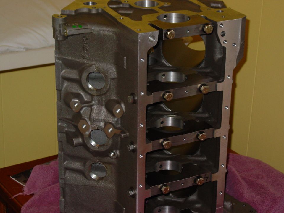 Bare aluminum V8 block stood on end showing cross-bolted main caps and bearing bulkheads