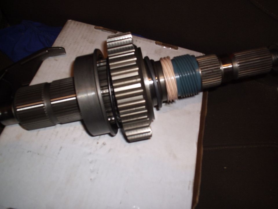 Splined transfer case output shaft with gear, bearing and seal laid on cardboard
