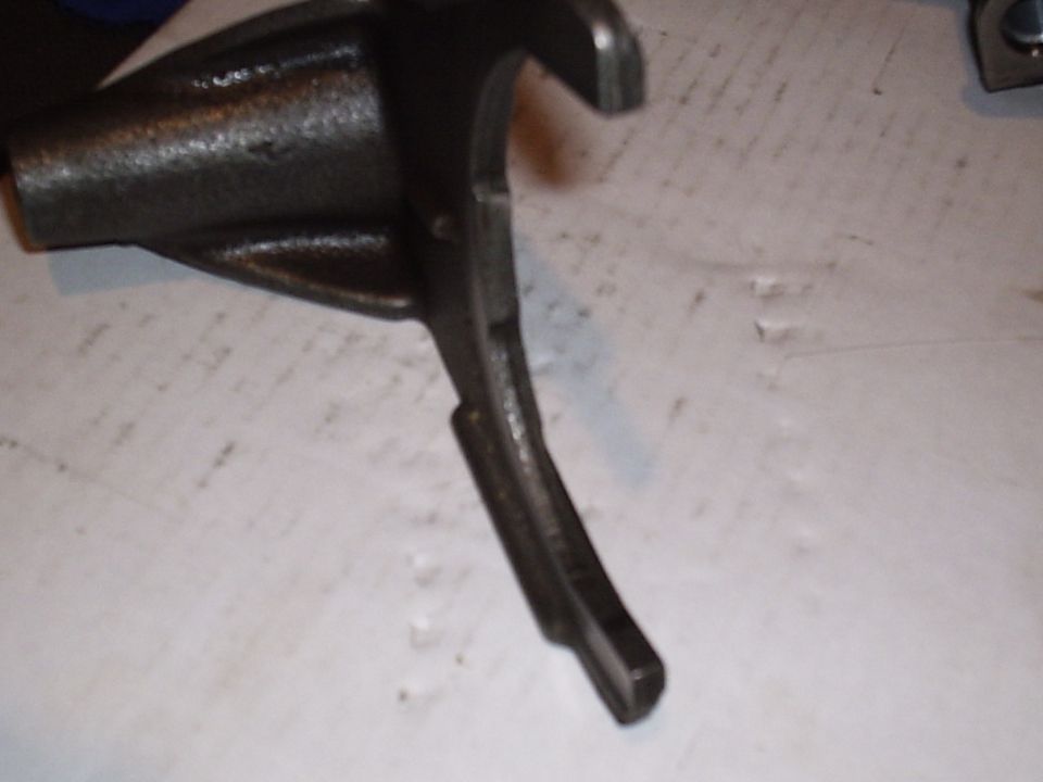 Close-up of a cast steel transmission shift fork on a white workbench