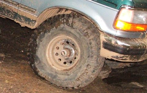 1996 Ford Bronco - This vehicle appears to be stuck in the mud, with its tire and fender heavily coated in dirt.