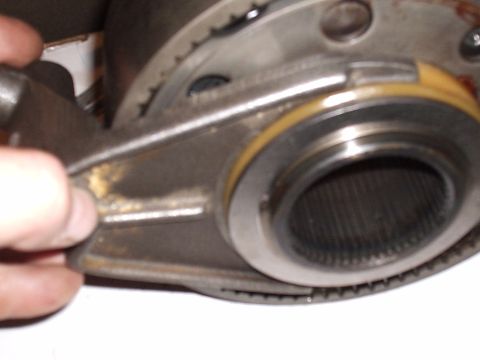 1985 Ford Bronco - Tight close-up inside a partly disassembled transmission or transfer case housing, with a hand holding a shift fork against a large splined…