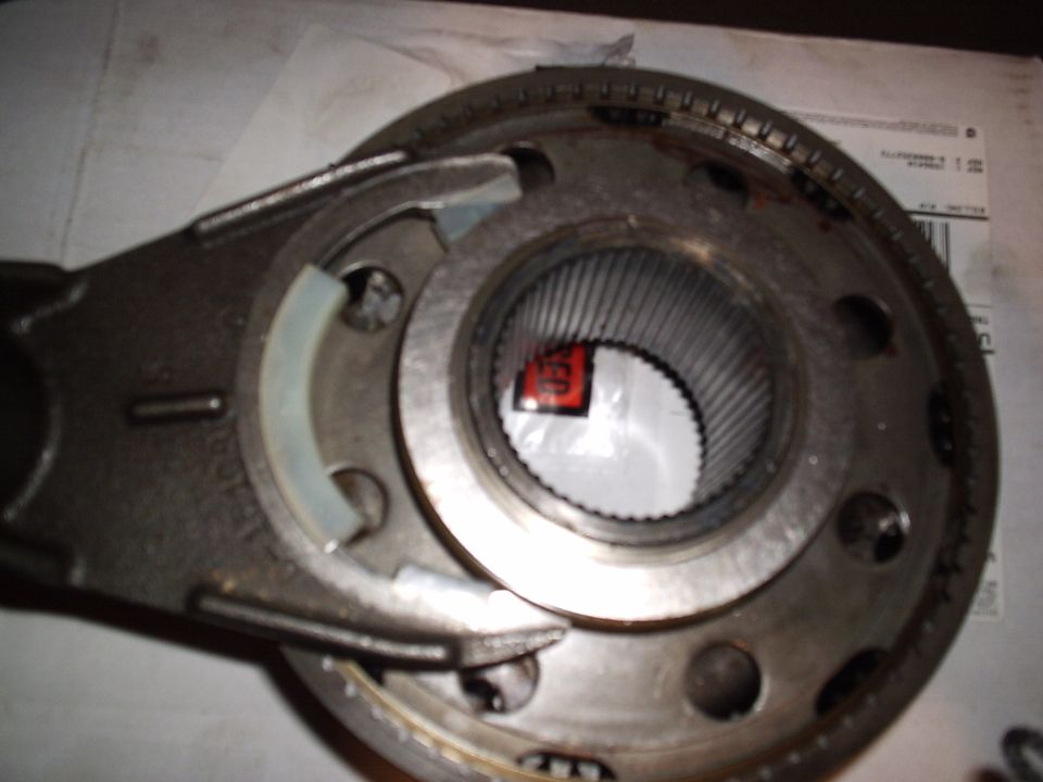 Shift fork engaged in a synchro sleeve on a splined hub, resting on a parts invoice