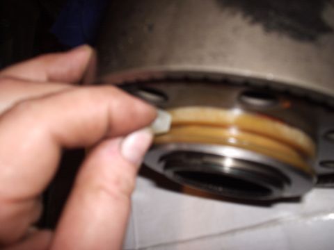 1985 Ford Bronco - A hand holds a small white plastic shift-fork pad or wear insert next to a disassembled transmission gear/clutch drum with brass synchro ri…