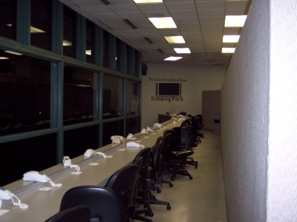Long press box row at Fenway Park with white phones and chairs along a counter