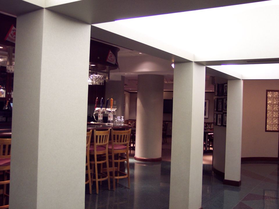Interior view of a bar with stools at the counter and tables in the background