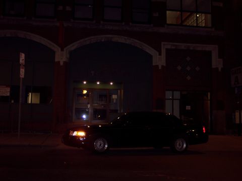 2001 Ford Crown Victoria - Black 2001 Ford Crown Victoria parked on street in front of a brick building at night.