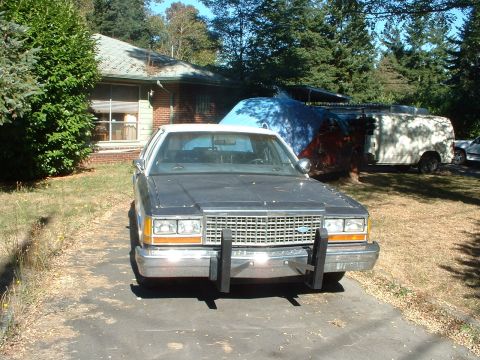 1999 Ford Crown Victoria - This 1987 Ford Crown Victoria police car is parked in front of a house, with other vehicles behind it.