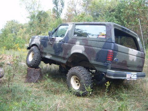 1988 Ford Bronco - This lifted Ford Bronco is shown off-roading with its front tire on a tree stump.