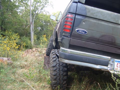 1988 Ford Bronco - This lifted Ford Bronco is positioned on a log, viewed from the rear with large off-road tires.