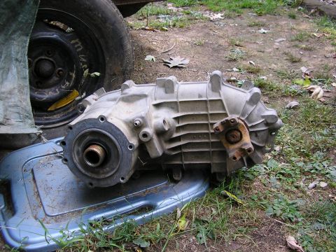 1991 Ford Bronco - A used transfer case sits on a tray outdoors, with a tire visible in the background.