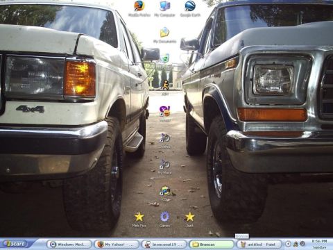 1978 Ford Bronco - Windows XP desktop screenshot whose wallpaper is a low front-corner shot of two Ford trucks nose-to-nose: a white one with 4x4 fender badgi…