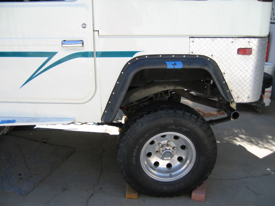 Rear quarter of white Land Cruiser with black flare, diamond plate corner and Dueler A/T tire