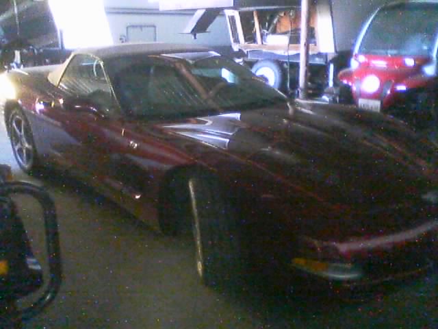 Dark maroon C5 Corvette parked in a garage next to a red SUV
