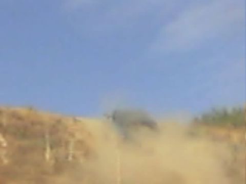 1990 Ford Bronco - vehicle kicks up a thick cloud of dust as it moves across a dry hillside under a blue sky.