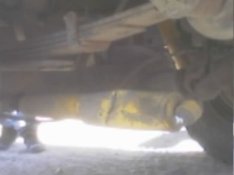 1990 Ford Bronco - underbody view of a vehicle showing a leaf spring, axle, and yellow-marked driveshaft components.