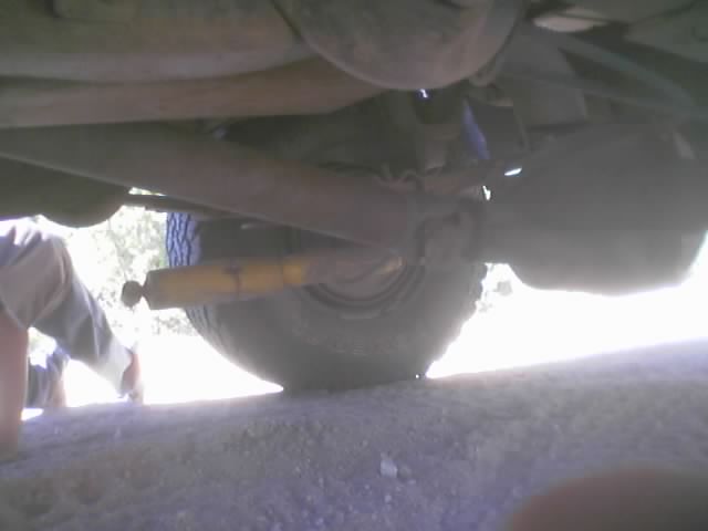 Low underbody shot of a vehicle's axle, tire and yellow shock absorber