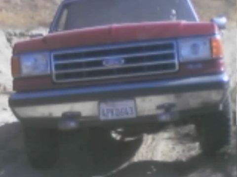 1990 Ford Bronco - front view of a red Ford SUV showing the Ford oval grille emblem, headlights, and a license plate.
