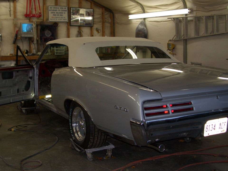 1967 Pontiac GTO convertible, silver, white top, interior visible, doors open, in garage