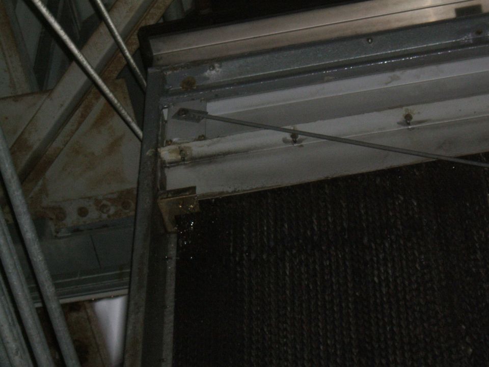close-up of a dark mesh panel with metal framing and some dripping water