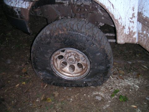 1994 Ford Bronco - A vehicle is stuck with a flat tire in a muddy area.