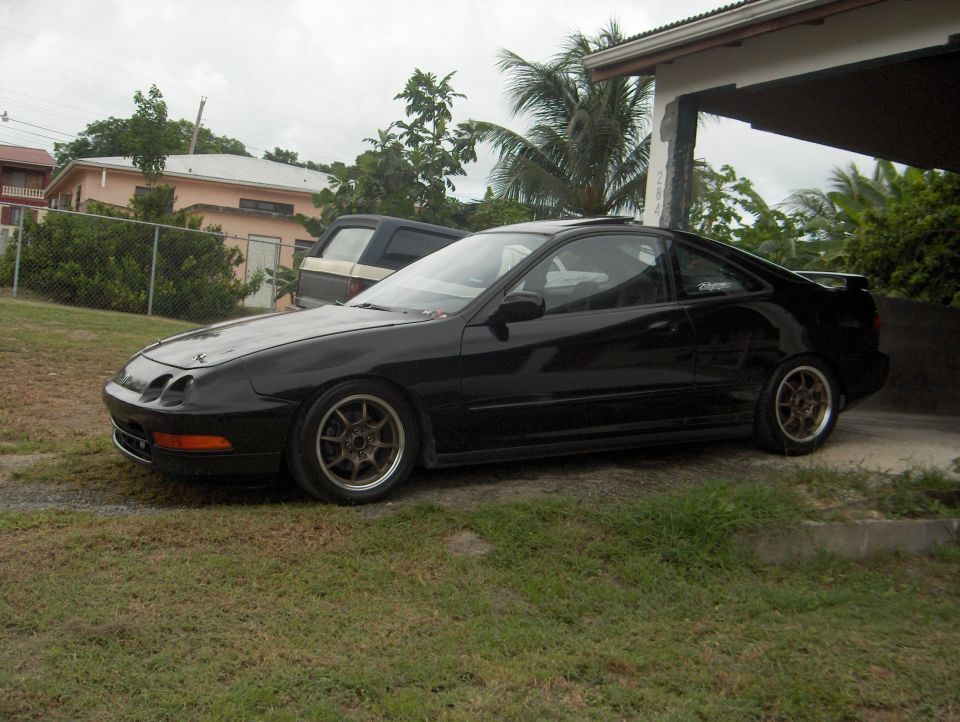 Black Acura Integra coupe lowered on bronze wheels by a carport