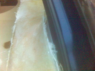 1994 Ford Probe - Close-up of a car's interior door panel, revealing unfinished fiberglass material and fabric.