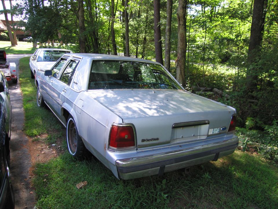 1991 Ford Crown Victoria LTD parked on grass, rear view. Another car is visible behind it