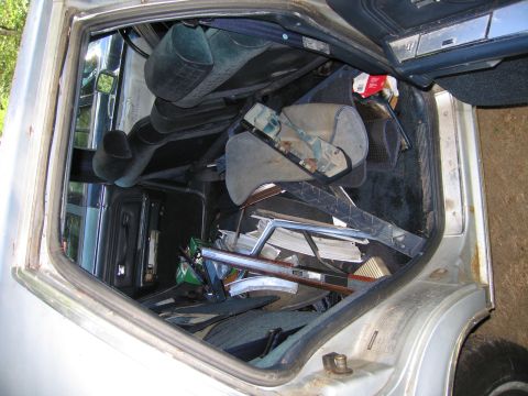 1991 Ford LTD Crown Victoria - The interior of a silver car is filled with various car parts and debris, obscuring the view of the seats and dashboard.