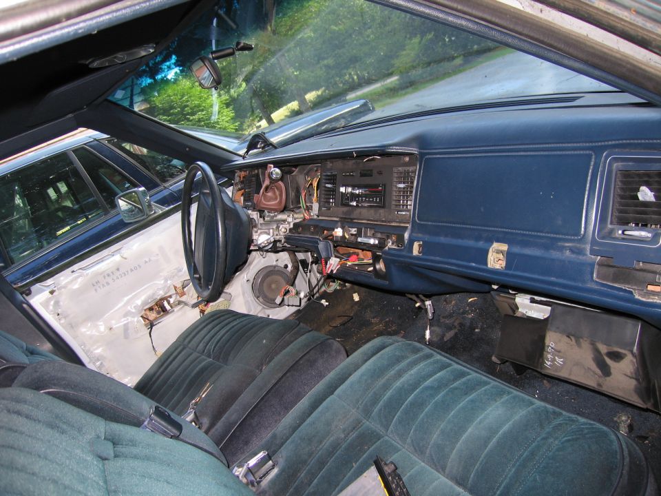 Interior of a car with dashboard removed, showing exposed wires and seats