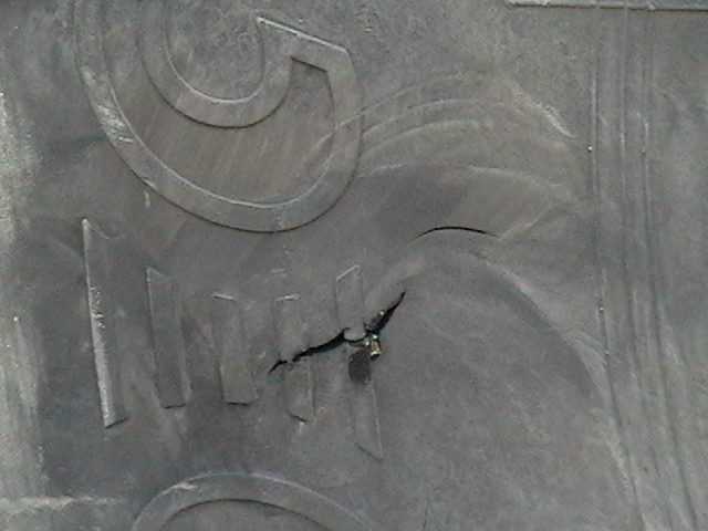 Close-up of gray embossed surface with a jagged puncture and torn damage
