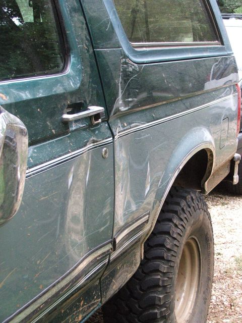 1996 Ford Bronco - The side panel of a green Ford Bronco shows damage from off-road use.