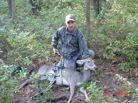 1995 Dodge 1500 - A hunter poses with a deer and bow in a forest clearing, with a SuperMotors watermark visible.